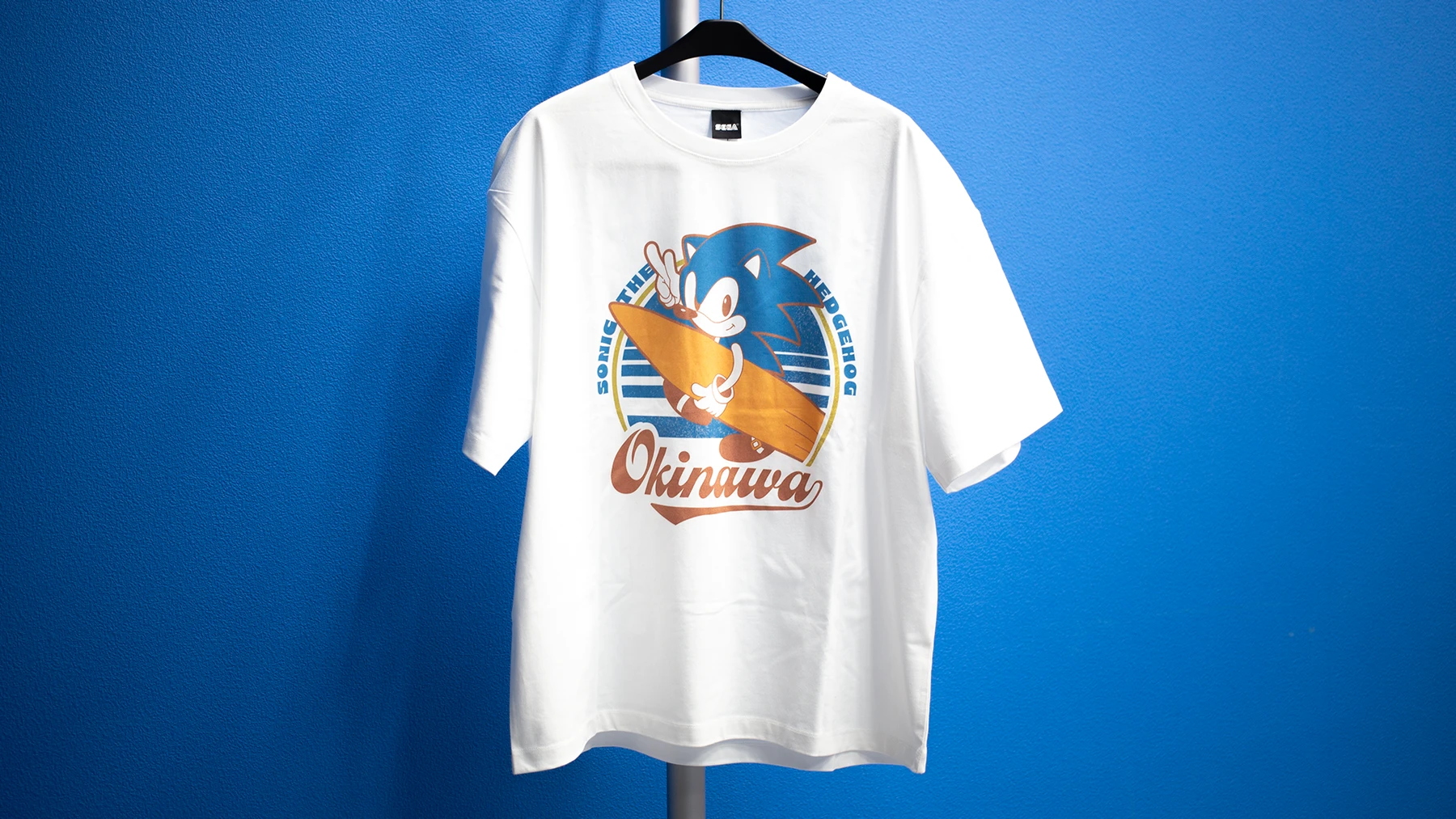 サーフボードを持つソニックのOKINAWA限定Tシャツ。メーカー案内5,500円（税込）。
